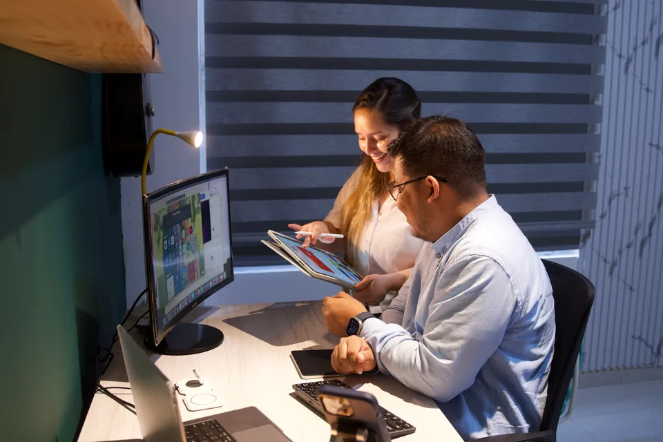 Dos integrantes de Global Bridge360 revisando un diseño en una tableta junto al computador